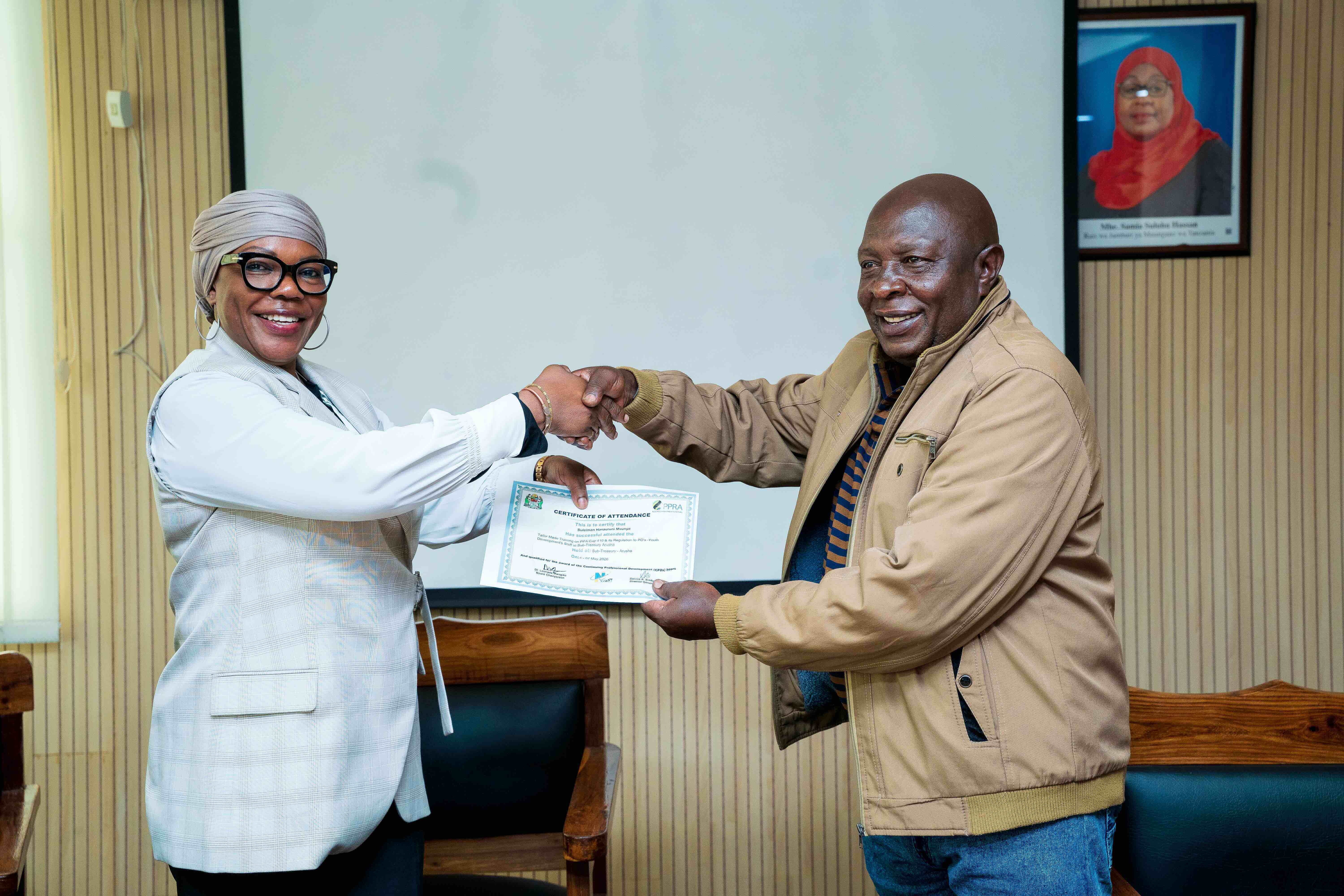 Mkurugenzi wa Utawala na Rasilimali Watu, Ofisi ya Rais – Maendeleo ya Vijana, Bi. Edith Simtengu, akimkabidhi cheti cha ushiriki katika mafunzo ya PPRA Mkurugenzi wa Idara ya Elimu ya Uzalen